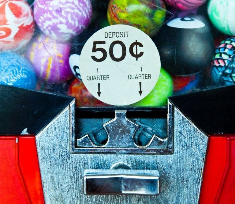 Close-up of a gumball machine with colorful candy and a 50¢ deposit sign.