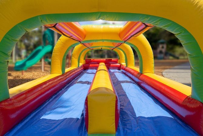 Colorful inflatable slide with red, yellow, blue, and green lanes outdoors