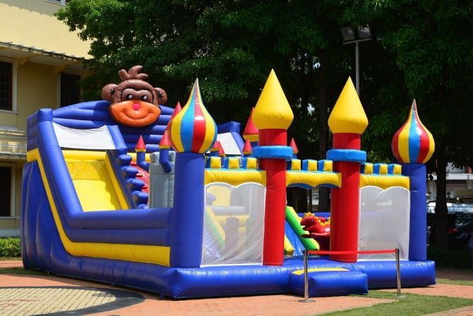 Colorful inflatable bounce house with slide and castle turrets in a sunny yard
