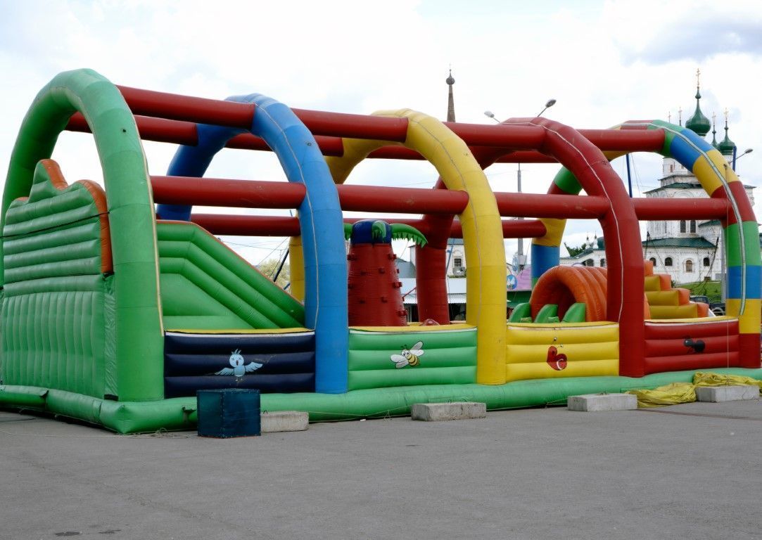 Colorful inflatable obstacle course with green, red, blue, and yellow arches outdoors on pavement