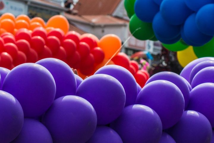 Clusters of colorful balloons in purple, red, orange, green, and blue at an outdoor event