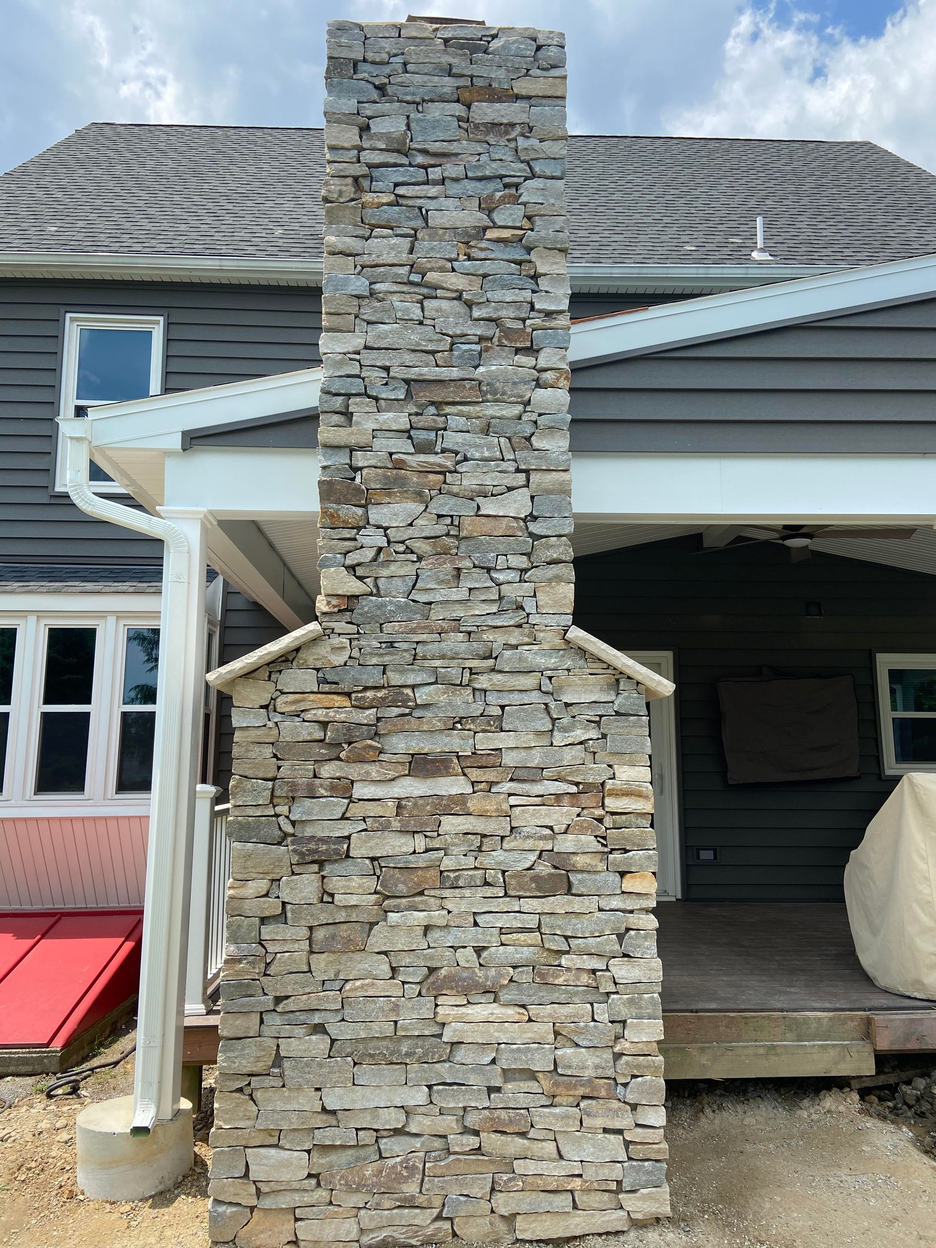 Stone veneer wall with gray, orange, and tan rectangular pieces arranged in a staggered pattern.