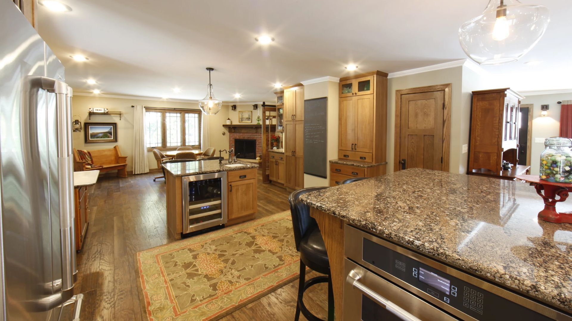 Spacious kitchen with wood cabinets, granite countertops, and stainless steel appliances. Hardwood floors and area rug.