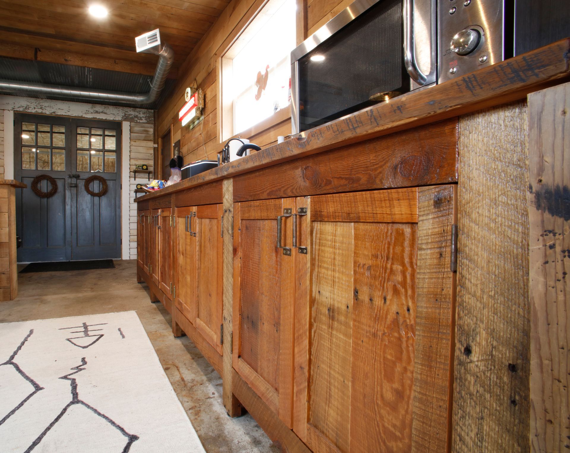 Bar with wood countertops, stone accents, pendant lights, and popcorn machine. Sliding barn door