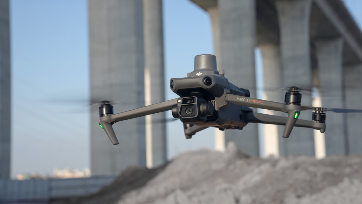 Un drone survole un tas de terre devant un pont.