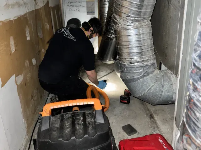 A man is cleaning the fans on the roof of a building.