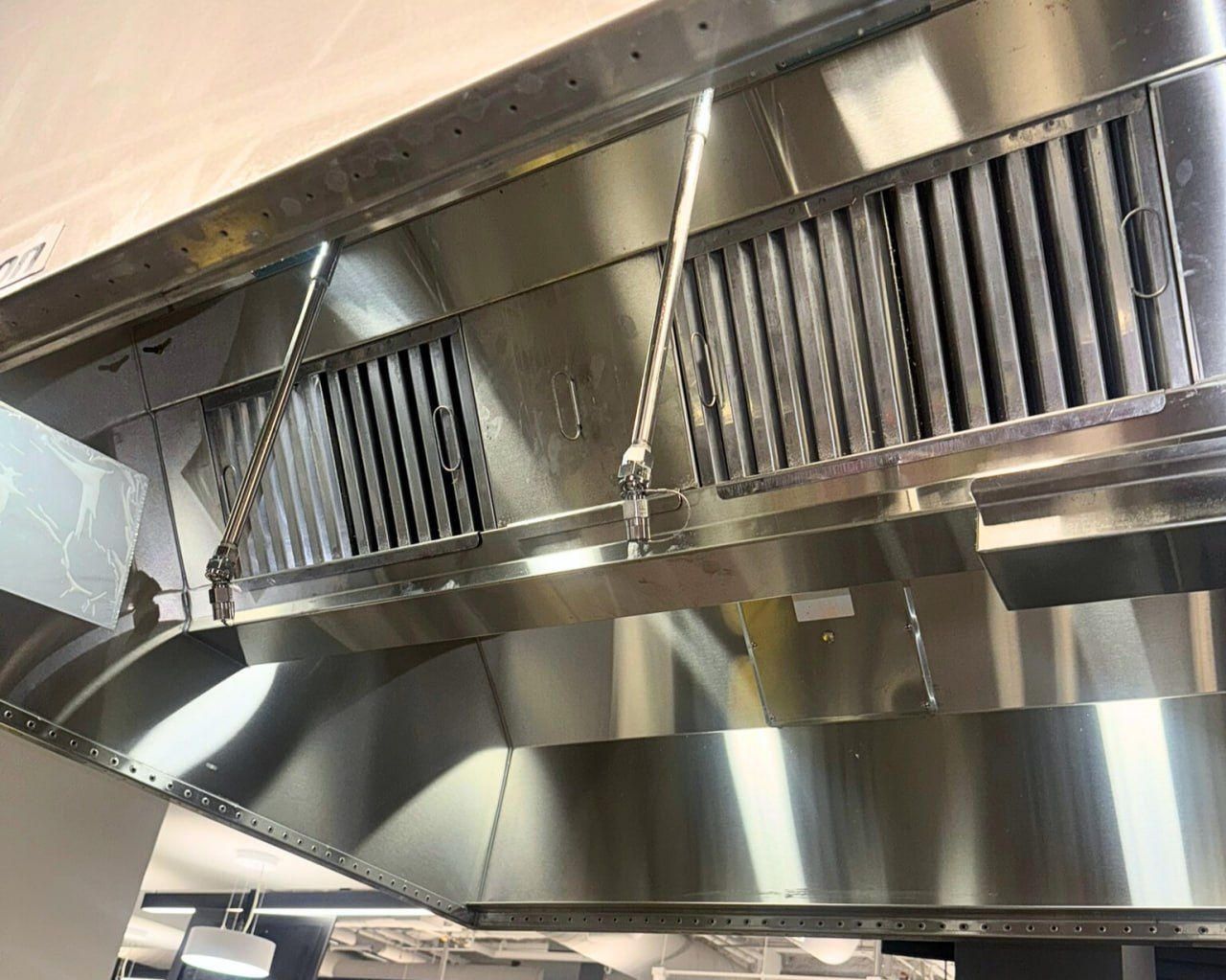 A man is cleaning the stove hood in a kitchen.