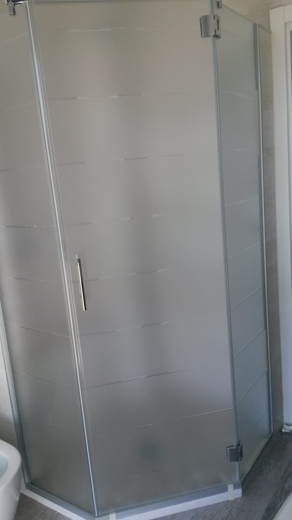 Box doccia angolare color argento con pannelli in vetro satinato e struttura cromata in un bagno