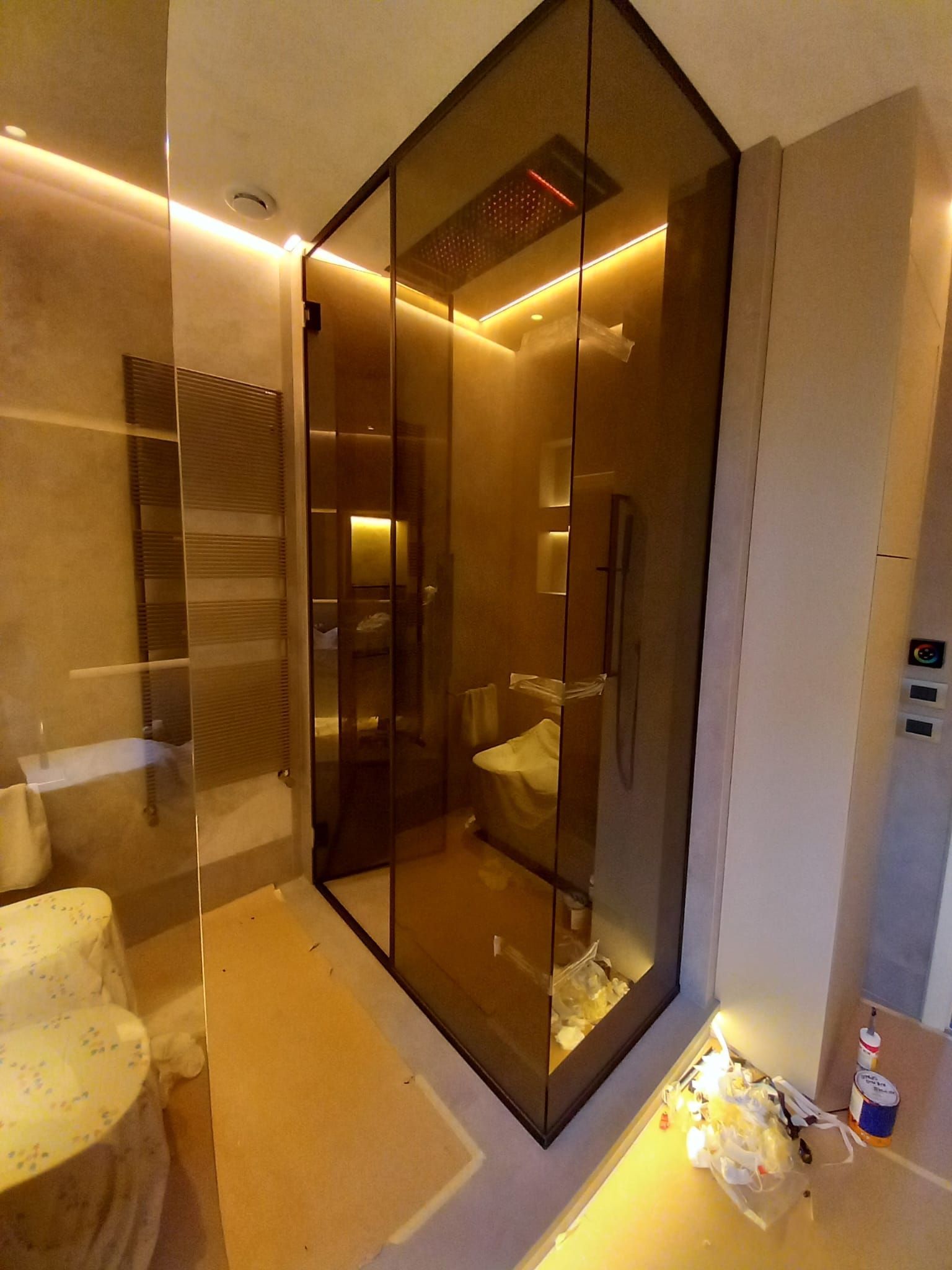 Bagno moderno con luce calda, box doccia in vetro e pareti rivestite di specchi.