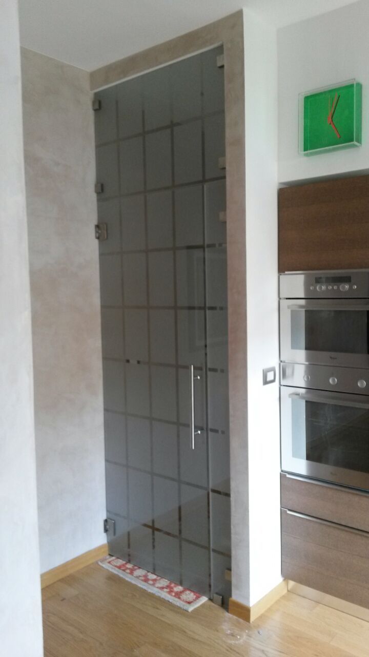 Porta d'ingresso moderna per la cucina con anta in vetro satinato, pavimento piastrellato e mobile con forno a incasso.
