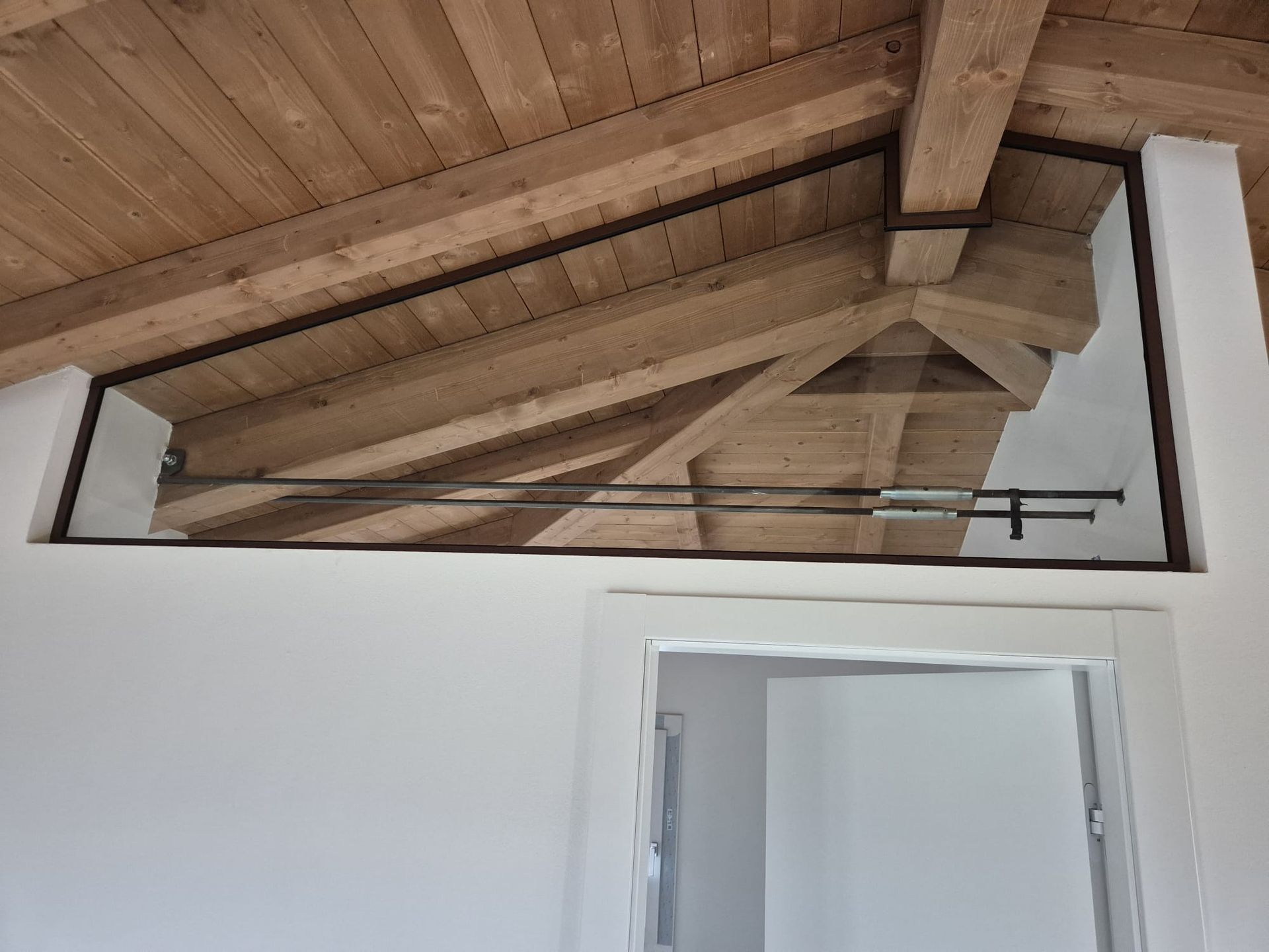 Soffitto a volta in legno sopra una porta bianca in una luminosa stanza interna