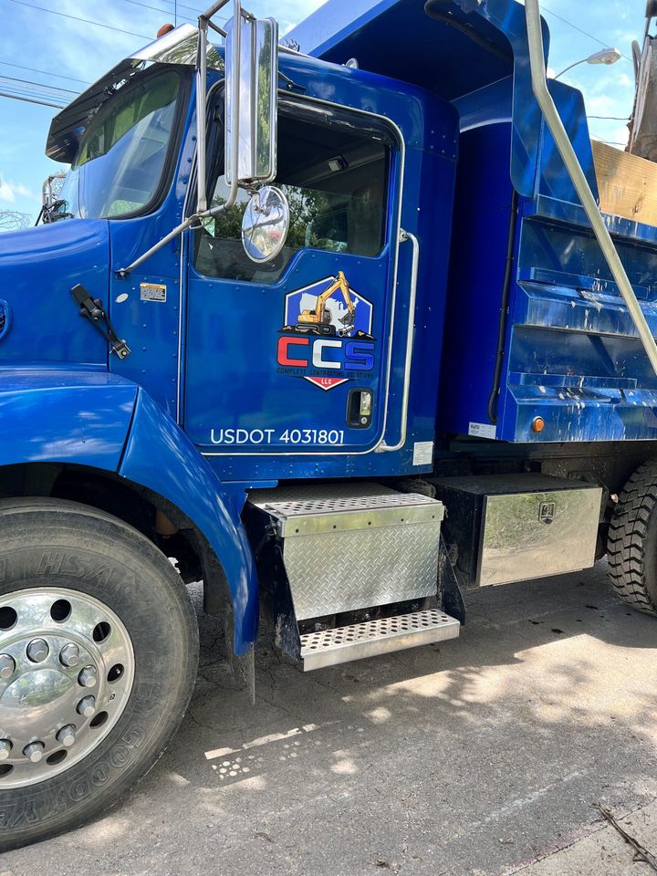 A blue dump truck is parked on the side of the road.