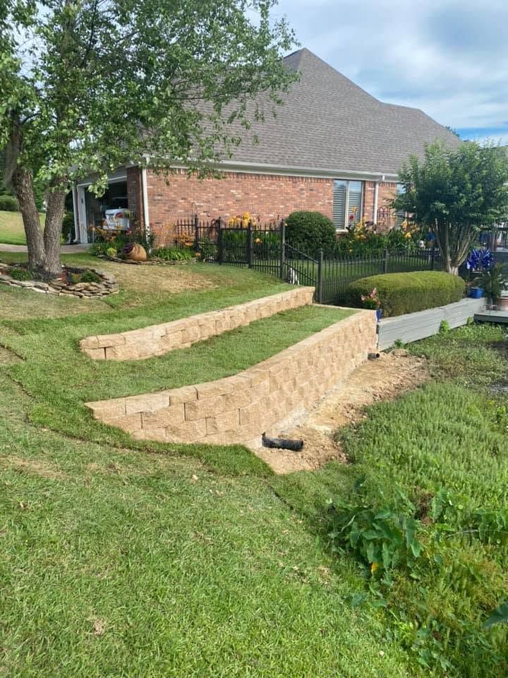 Terraced brick steps in a grassy backyard beside a house, with shrubs and a tree nearby