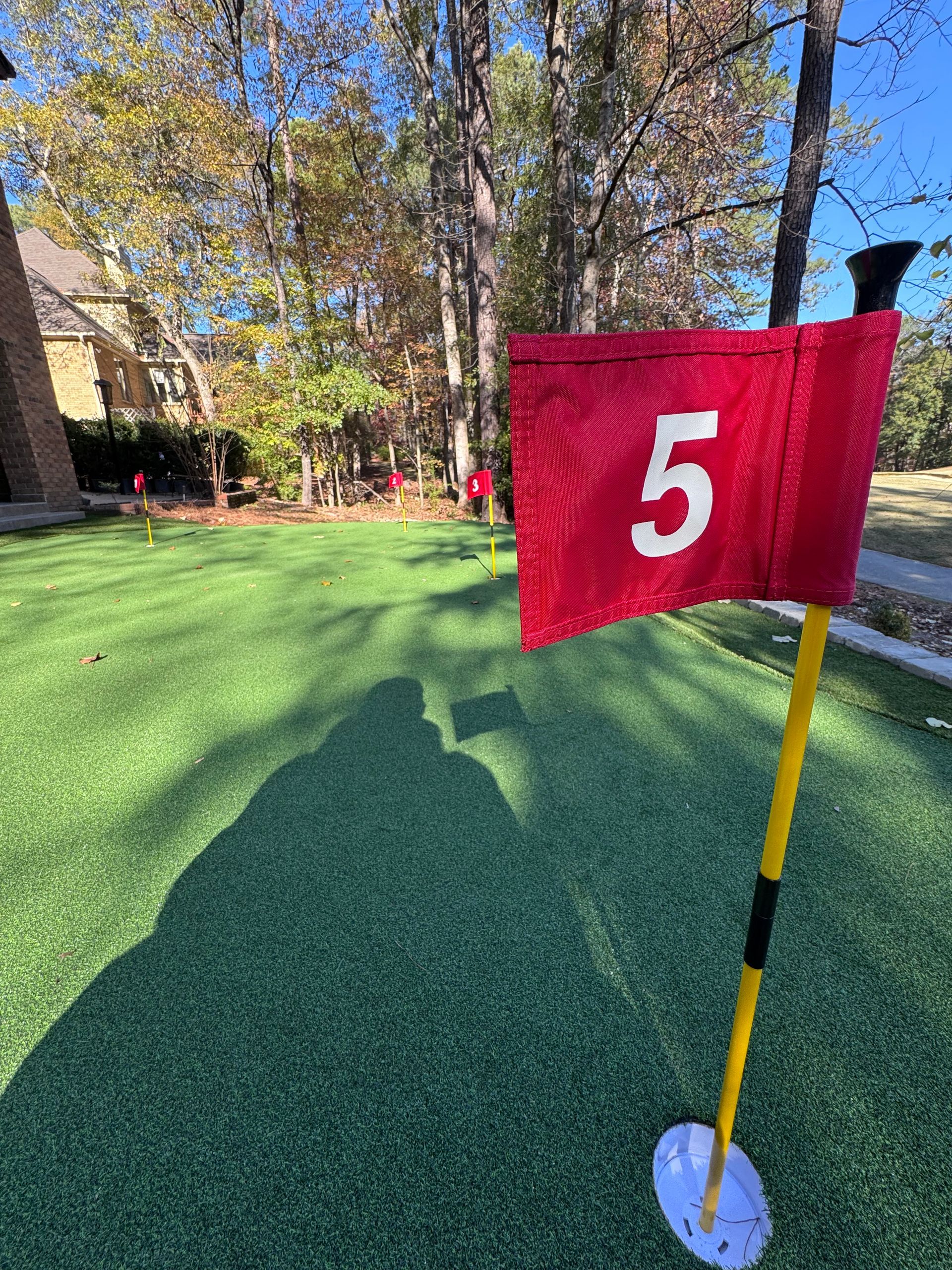 A red flag with the number 5 on it is on a golf course.