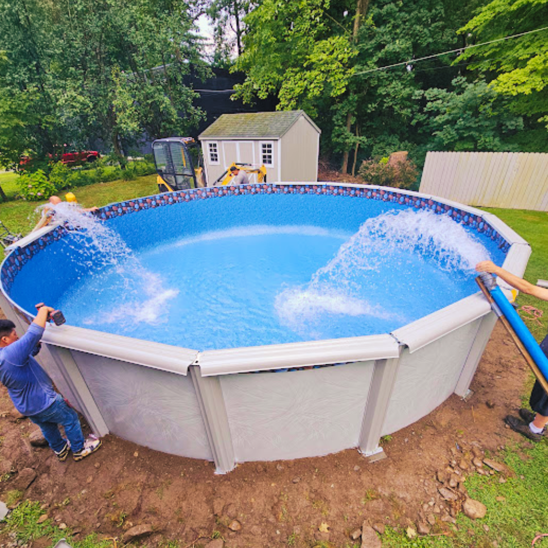 Above-ground pool being filled with water in a backyard, with two people holding hoses and a shed nearby Above-ground pool being filled with water in a backyard, with two people holding hoses and a shed nearby