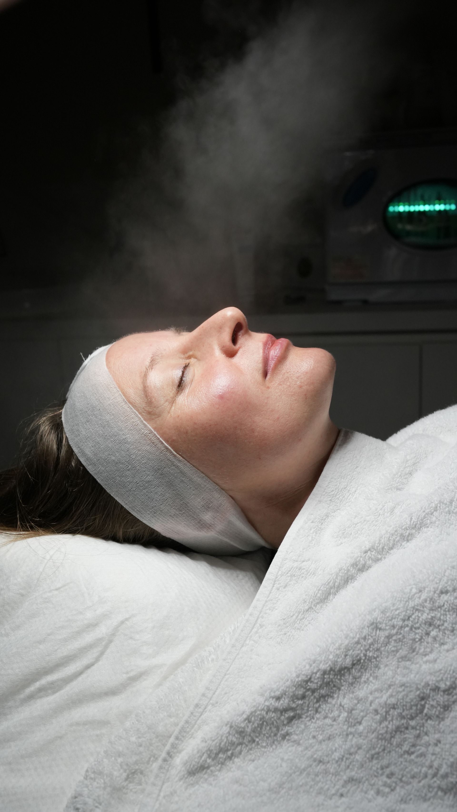 Woman in bikini and shirtless man sitting in sauna, illuminated by blue light.