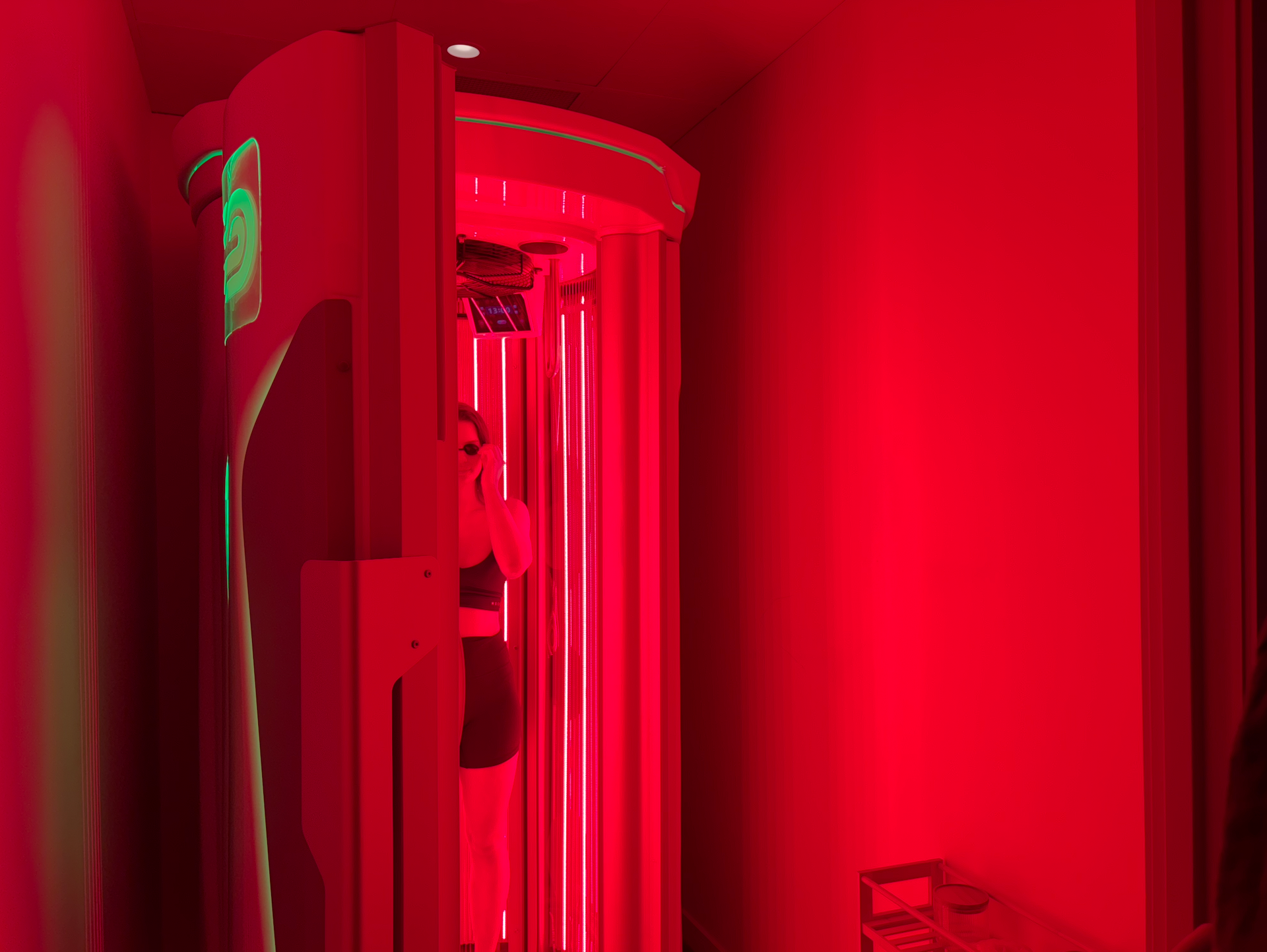 Woman in black bikini seated cross-legged in a sauna, with blue and amber lighting.