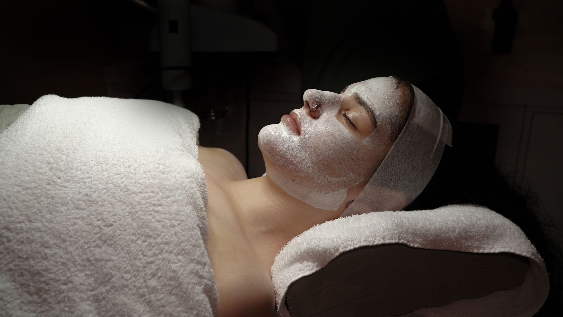 Woman in bikini and shirtless man sitting in sauna, illuminated by blue light.