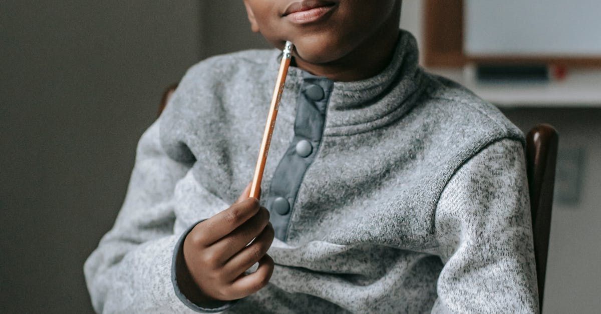 A young boy is sitting in a chair holding a pencil.
