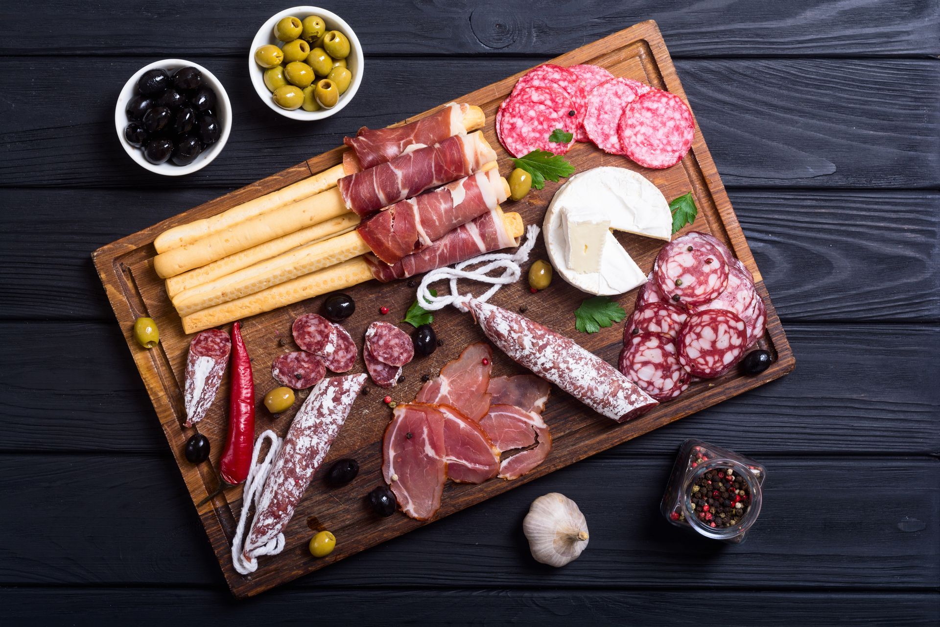 A wooden cutting board topped with a variety of meats and cheeses.