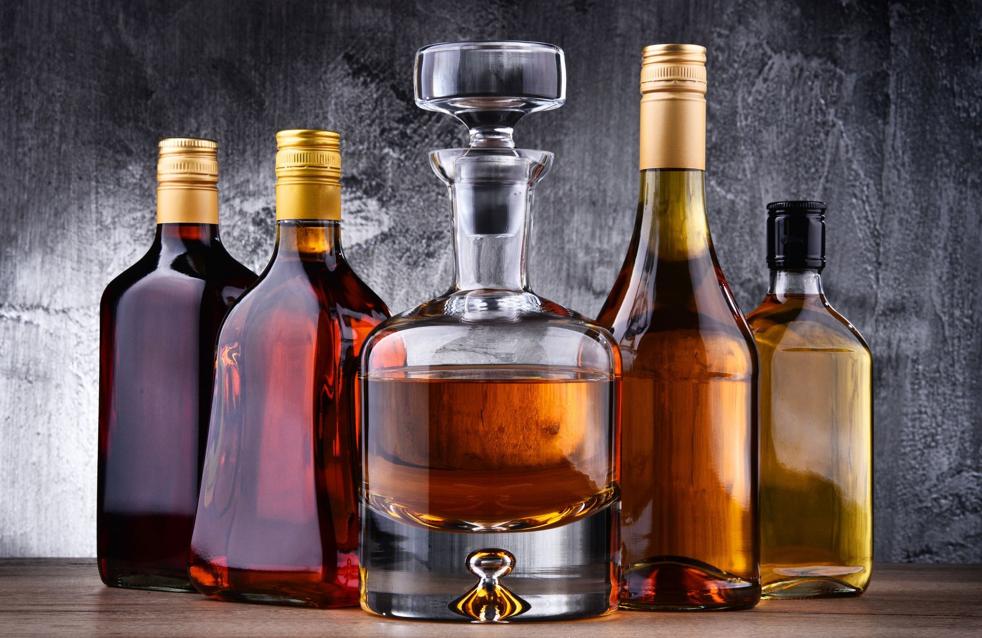 A group of bottles of alcohol are sitting on a wooden table.