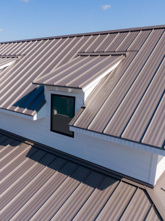 Metal rooftop with a dormer window and skylight under a clear blue sky