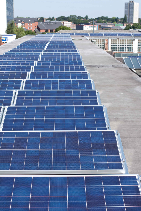 A row of solar panels on the roof of a commercial building