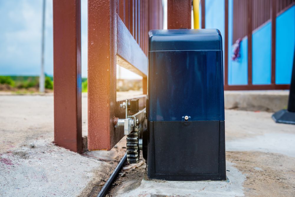 A Sliding Gate Motor is Sitting Next to a Sliding Gate — Airlie Beach Garage Doors In Airlie Beach, QLD