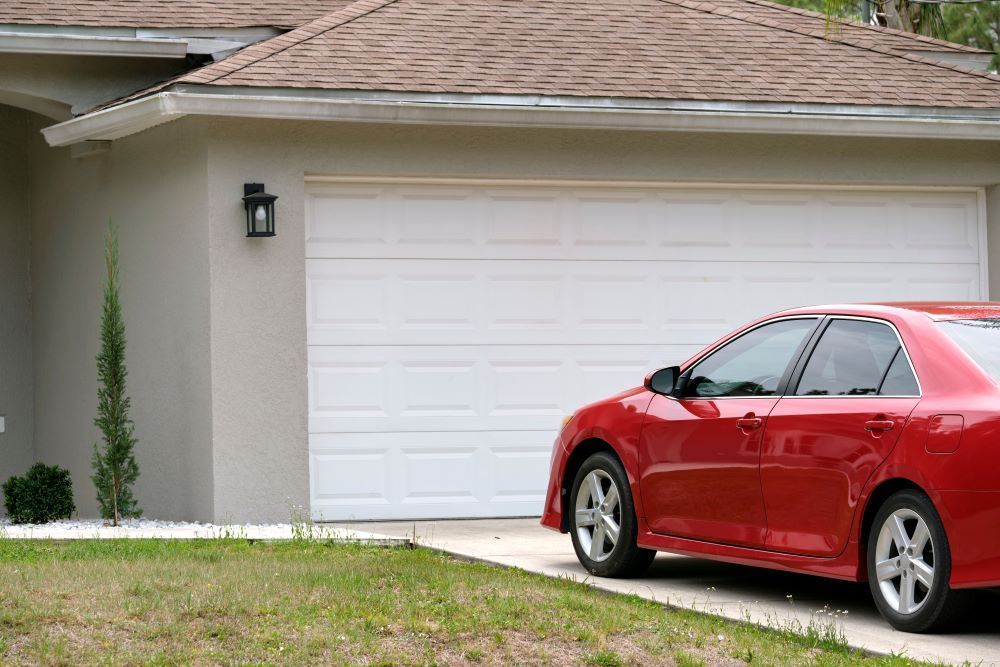 A Red Car Parked Outside a House — Airlie Beach Garage Doors In Cannonvale, QLD