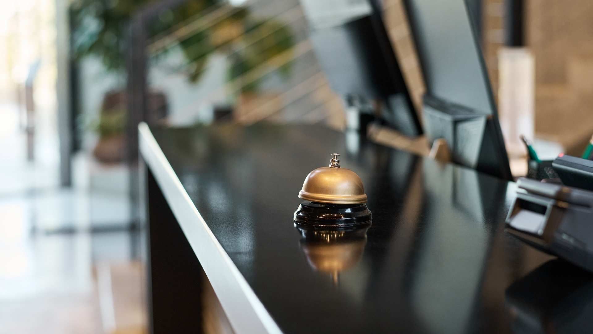 Hotel reception bell on a glossy black counter near a modern front desk