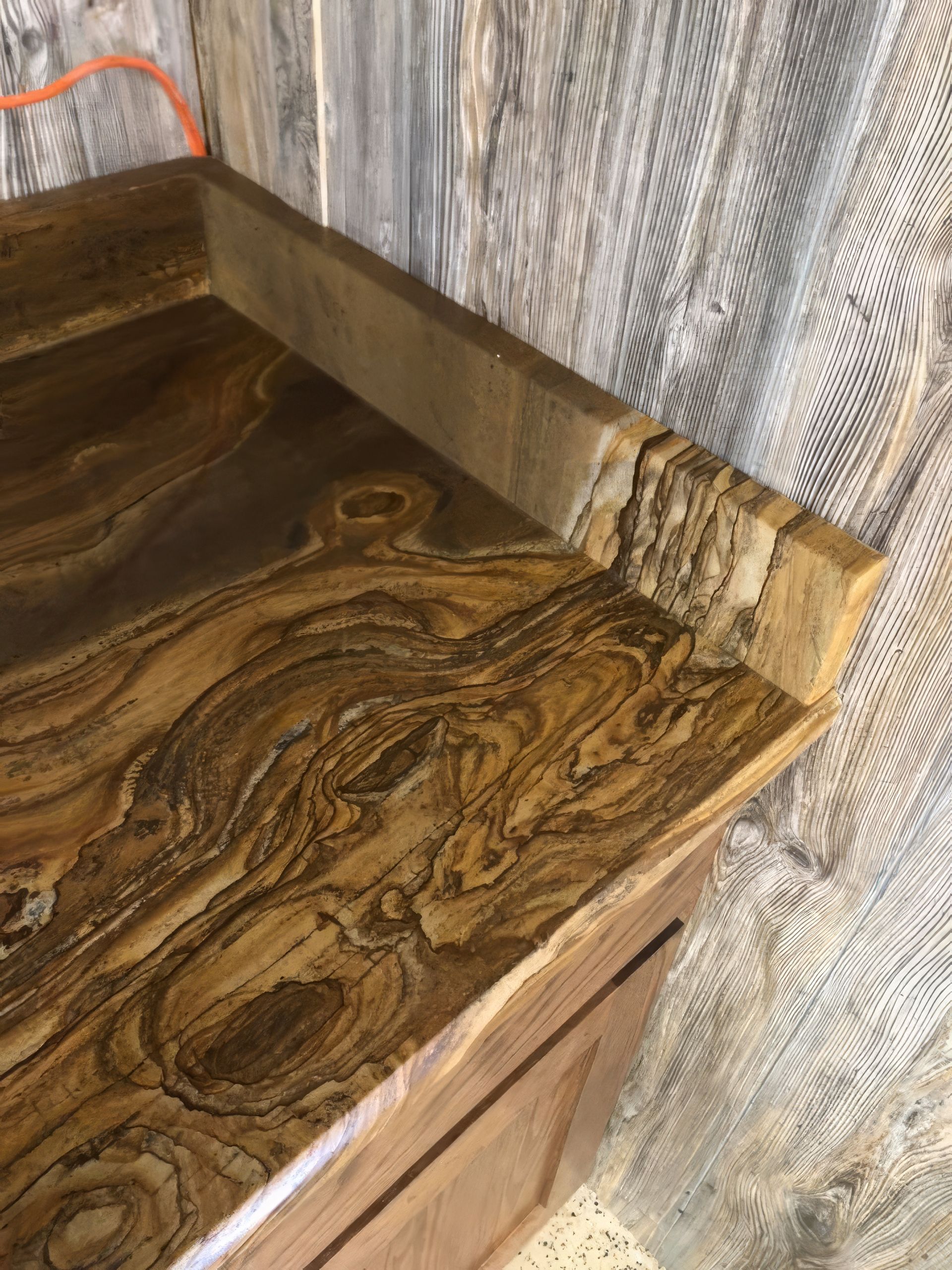 Wooden countertop corner with water damage and a taped, stained backsplash area