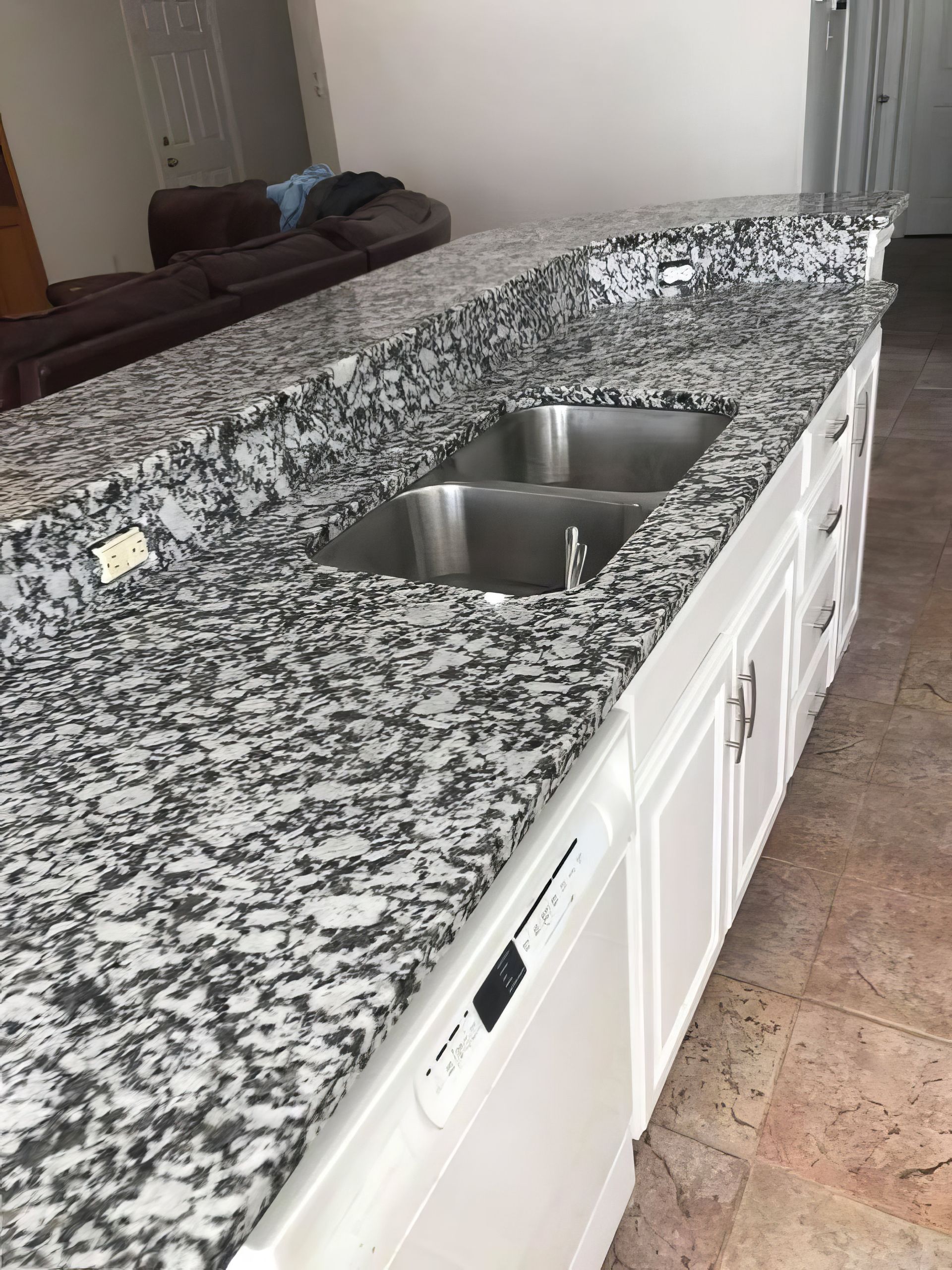 Granite kitchen countertop with double stainless steel sink and white cabinets