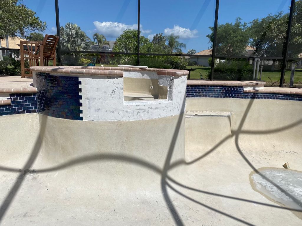 Backyard pool with a built-in bar and stools, blue tile, and a fenced patio under a clear sky