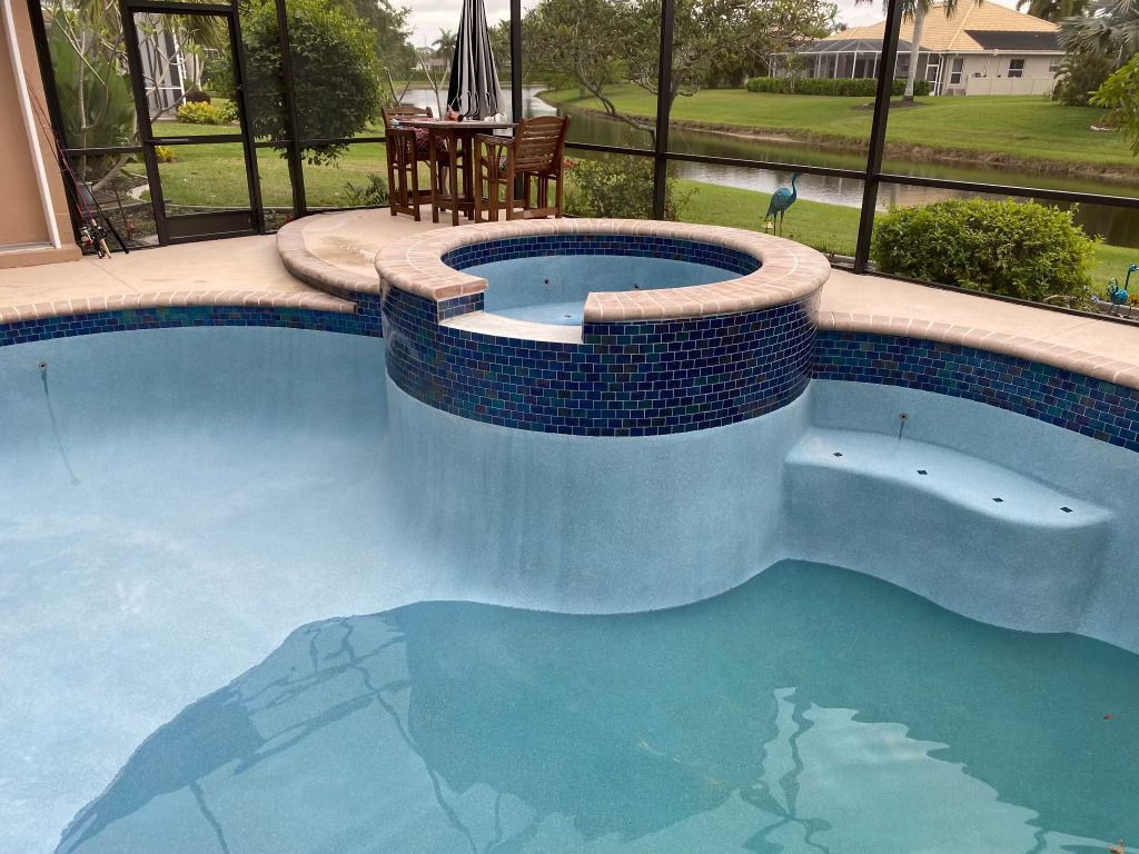Screened backyard pool with a raised circular spa and blue tile seating bench