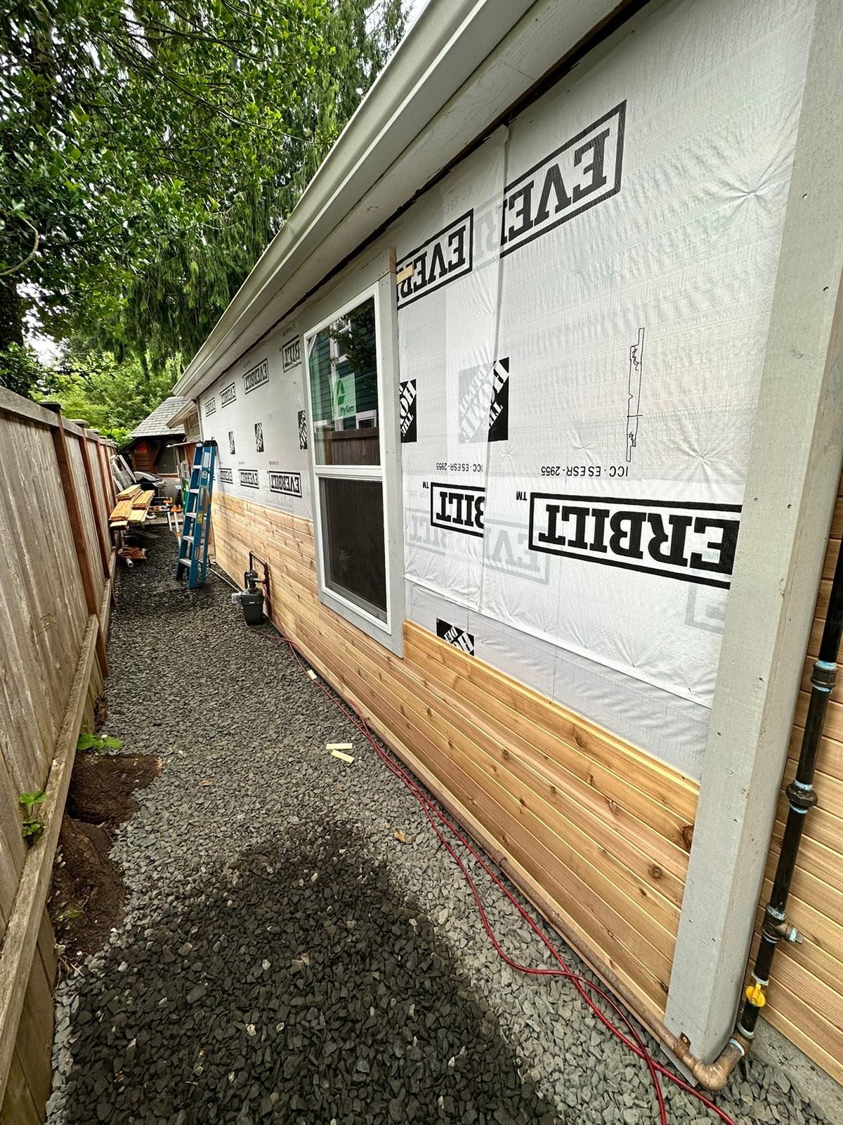 House exterior under construction, with new siding being installed.