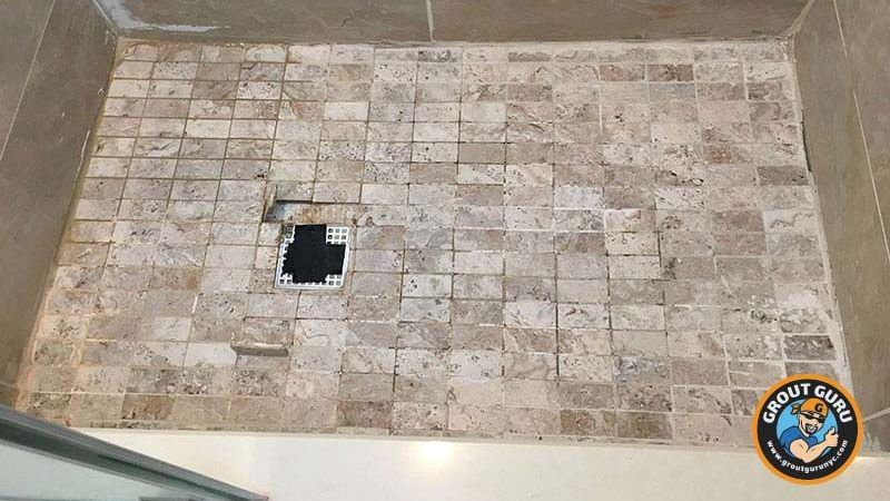 A tiled shower floor with a drain hole in the middle.