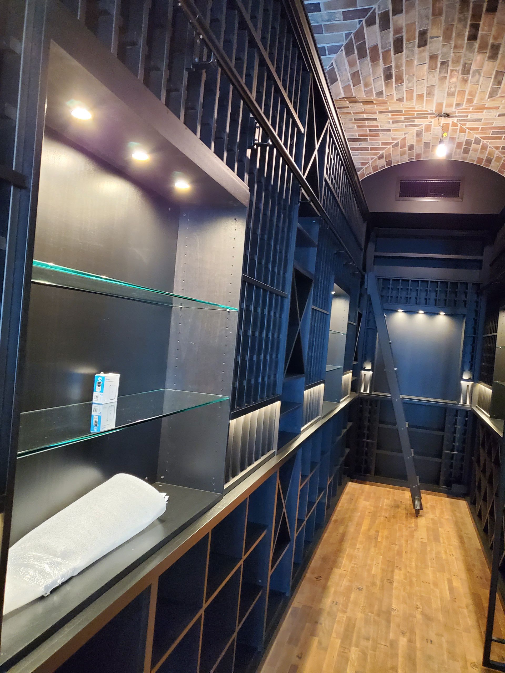 A long hallway with shelves and a ladder in the corner