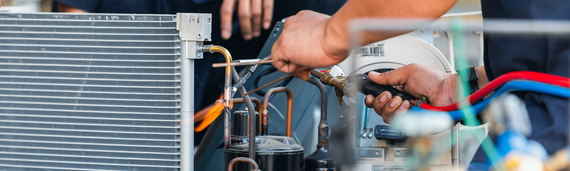 Technician repairing a car engine with tools near the radiator and wiring in a workshop
