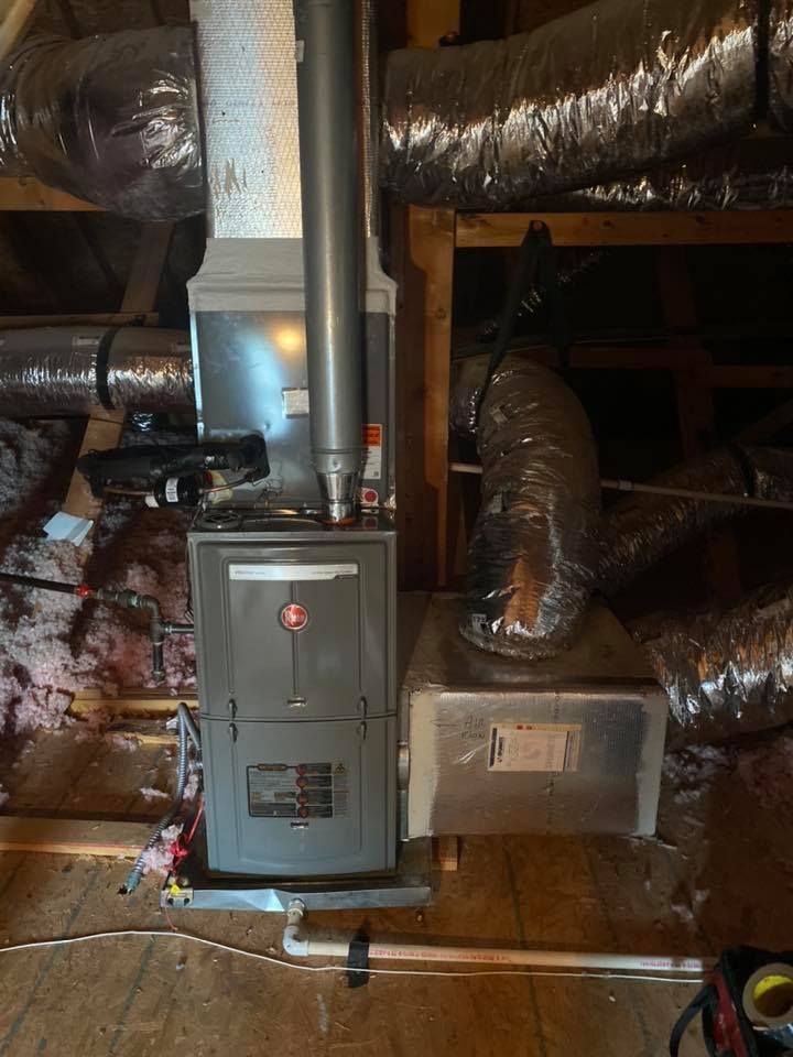 Basement furnace and HVAC ductwork with gray metal units and insulated pipes