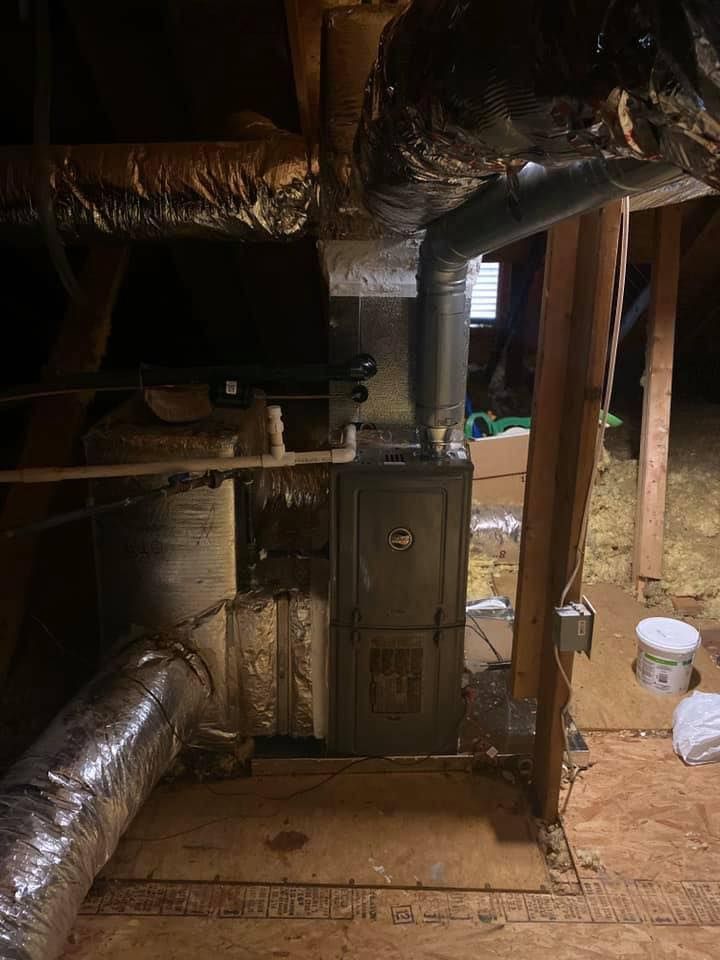 Basement furnace with exposed insulated ducts and pipes in a utility space