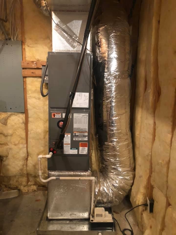Furnace and ductwork in an unfinished basement with exposed insulation and wooden framing