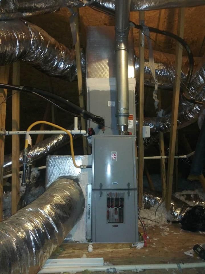 Basement HVAC furnace with ductwork and pipes in an unfinished utility room