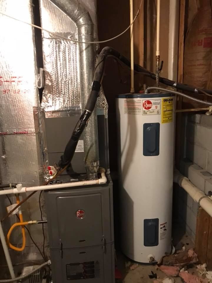 Basement utility area with a water heater, furnace, and ductwork near a wall.