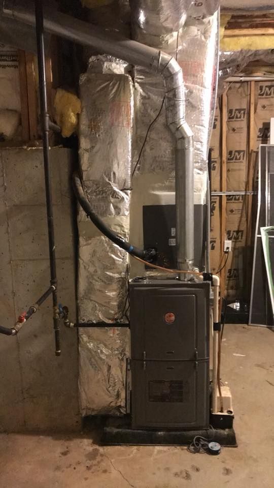 Basement utility room with a furnace, silver ductwork, exposed framing, and storage items.
