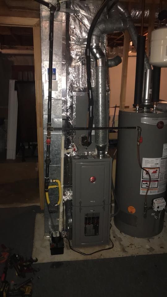 Basement utility room with furnace, water heater, and exposed ductwork and pipes.