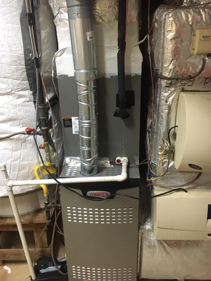 Basement HVAC furnace with metal ductwork, vents, and insulated pipes against a foil-covered wall