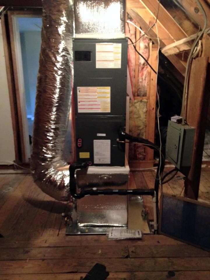 Furnace and ductwork in an unfinished attic space with exposed insulation and wooden framing.