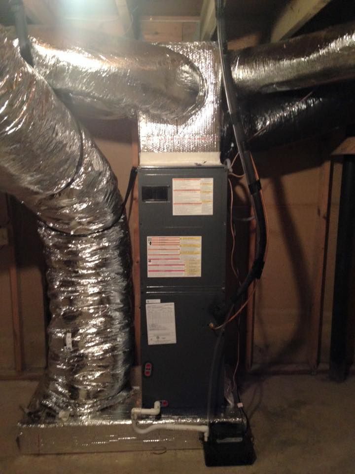 Basement furnace with large silver ventilation ducts and exposed utility lines