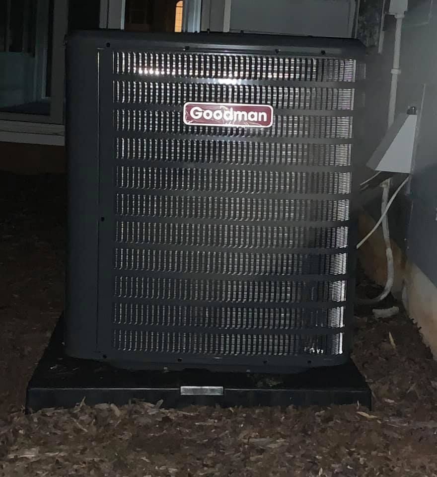 Goodman outdoor air conditioner unit beside a house at night