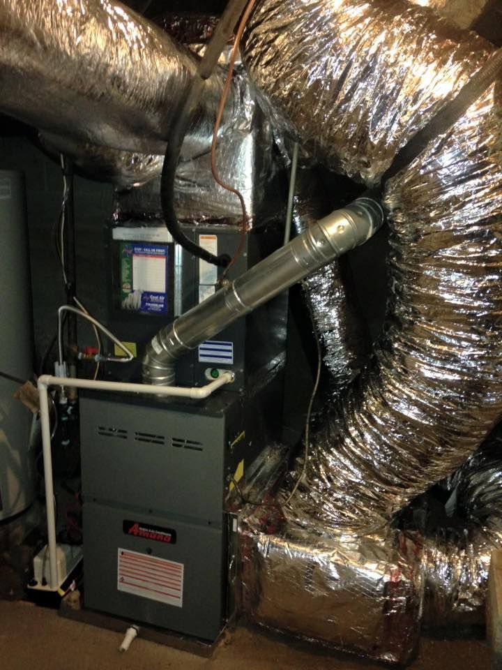 Basement HVAC furnace with silver ductwork and insulated pipes in a utility room